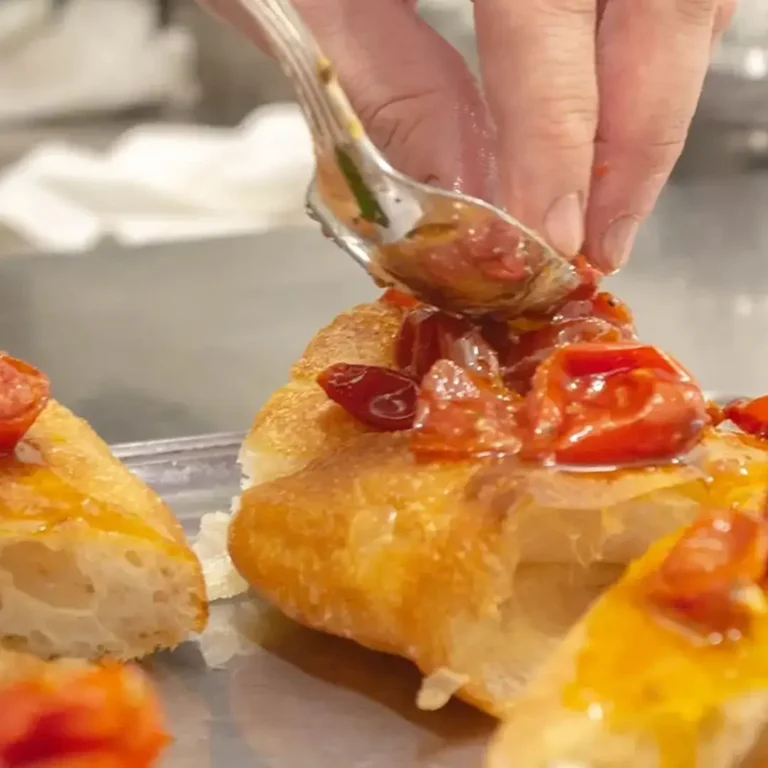 Lo chef condisce la focaccia con pomodorini freschi nella cucina del San Pietro Bistrot