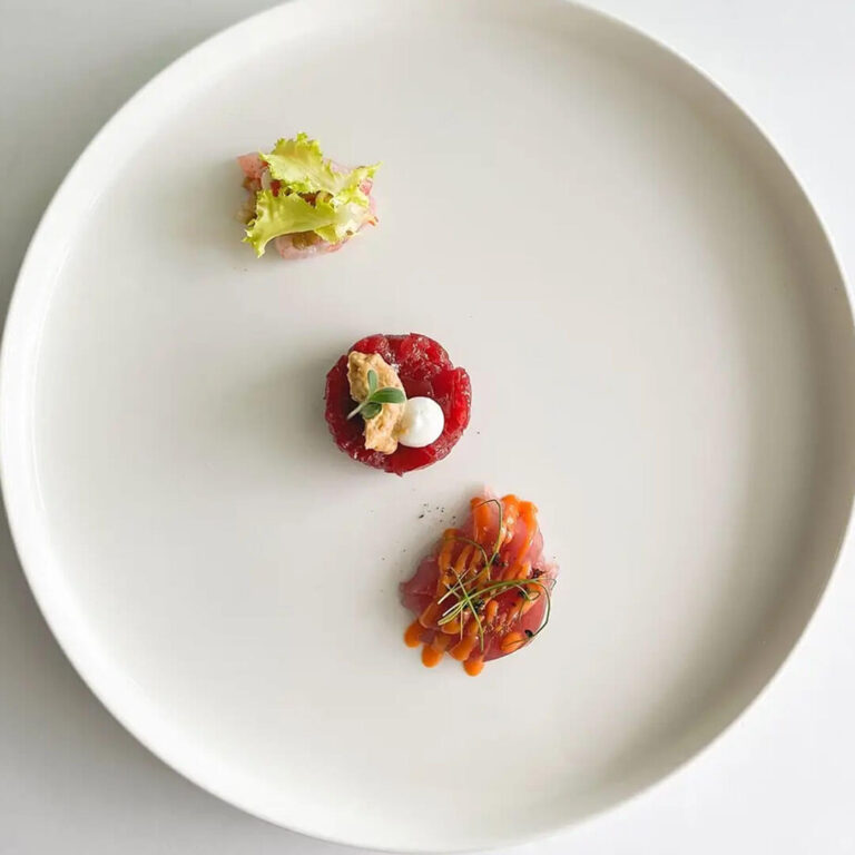 Tre assaggi di crudo di mare serviti su piatto bianco