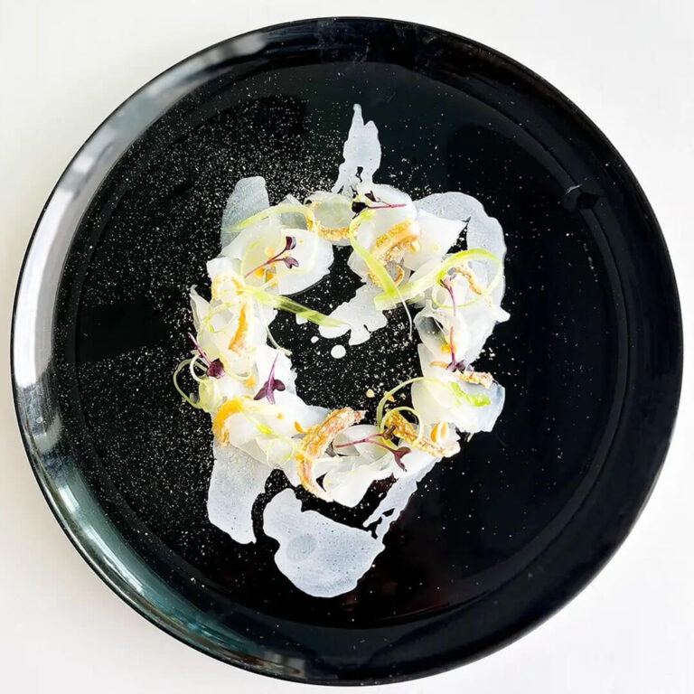 Crudo di pescato del giorno con agrumi e germogli su piatto nero