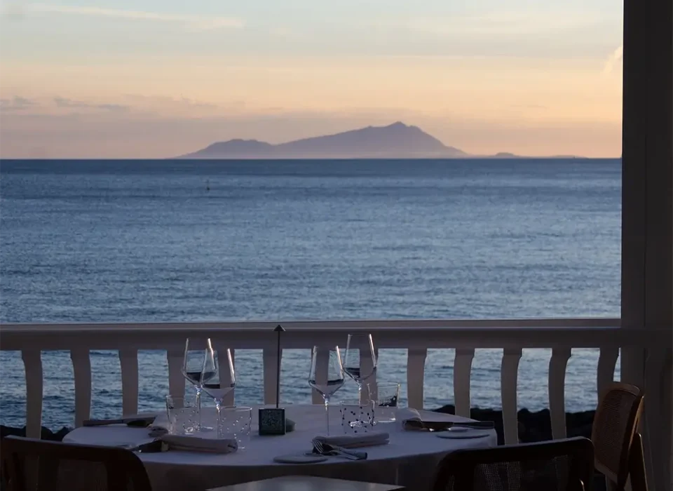 Tavolo apparecchiato sulla terrazza affacciata sull isola d'Ischia e il Golfo di Napoli al tramonto